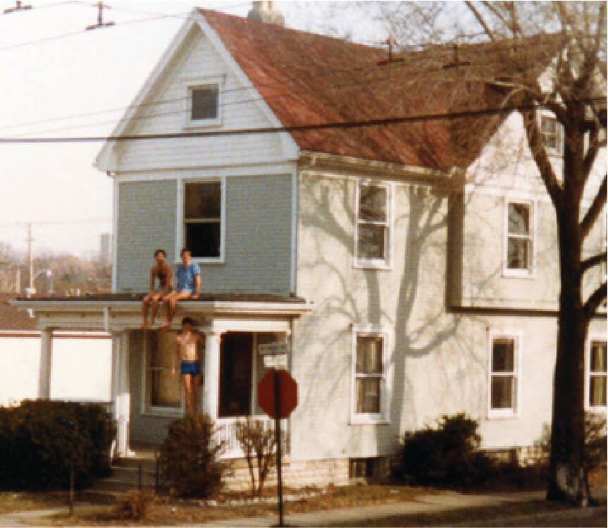 gray house with three young men on porch